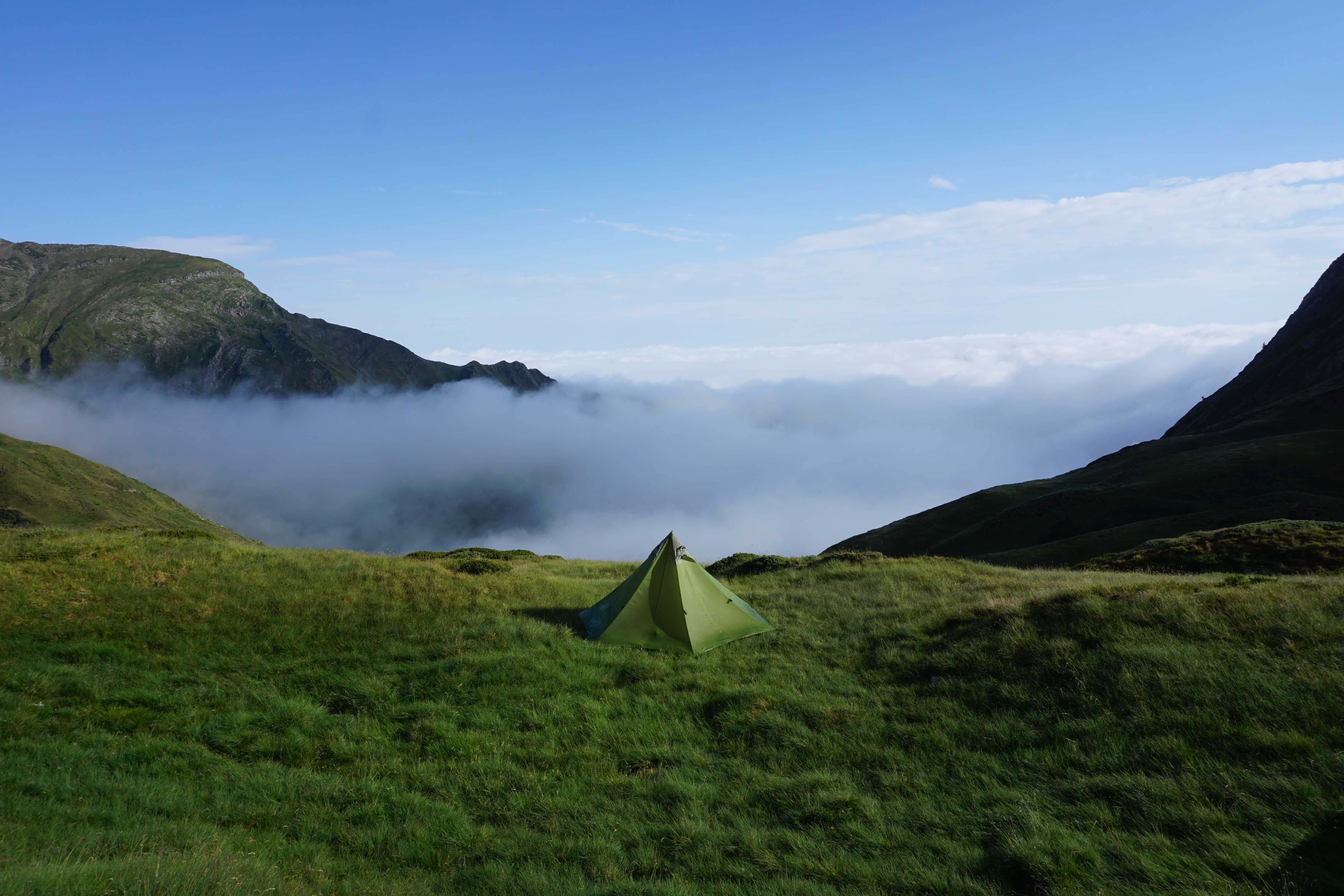 Triangular go light tent pitched on a mountain with cloud in the valley below
