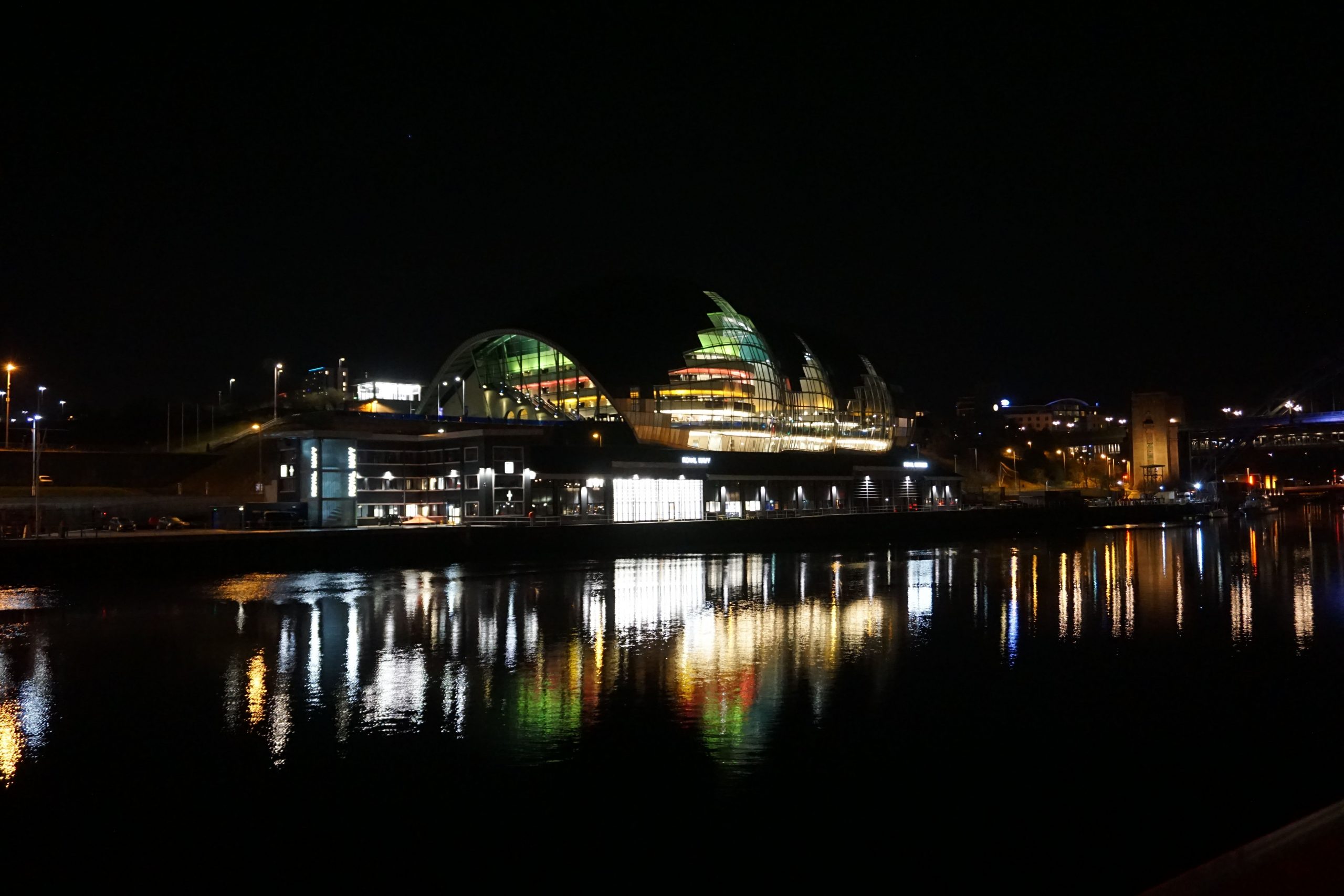 Gateshead Sage building from across the river, the colored lights are reflected in the river Tyne.