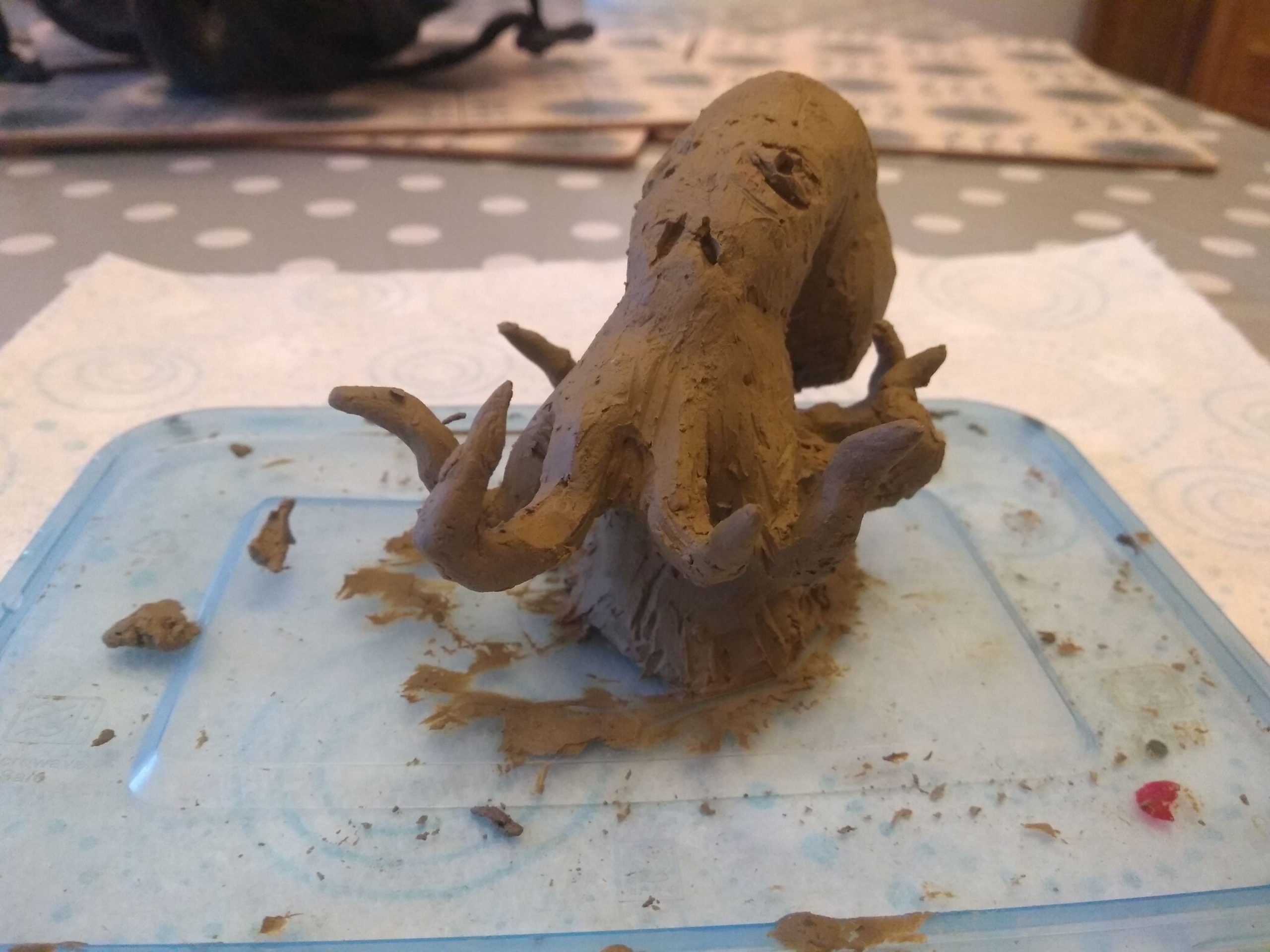 Clay sculpture of an octopus, its tentacles are rearing up around it.