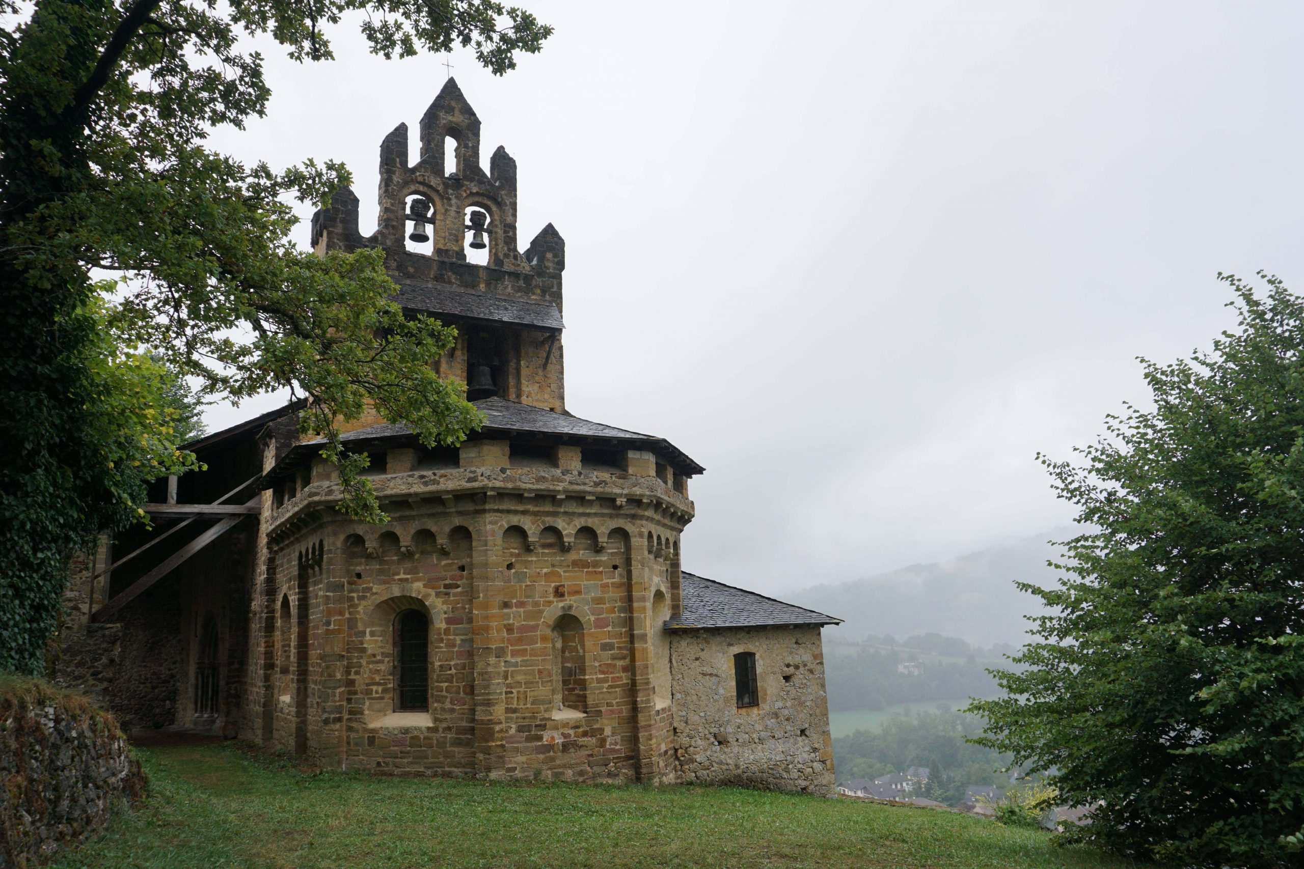 Stone chapel on the edge of a misty hill, three bells in the steeple.